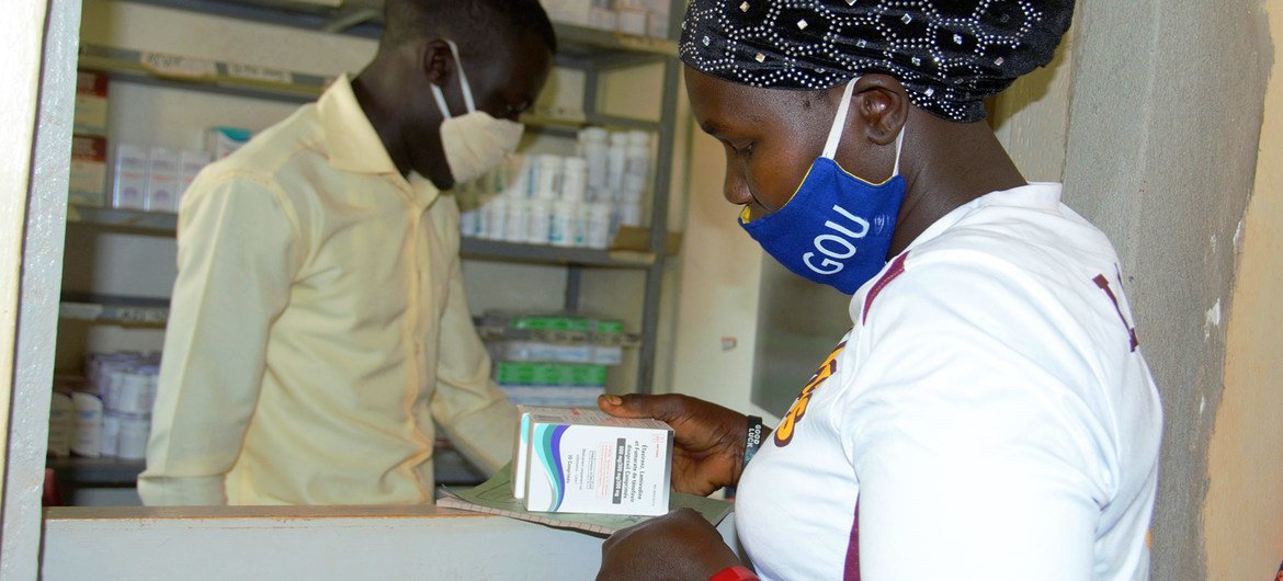 Una mujer que vive con el VIH recibe su medicación en un centro de salud de Uganda durante la pandemia de COVID-19.