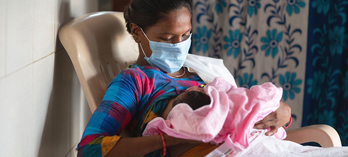 Una mujer amamanta a su bebé en una sala de partos en India poco después de dar a luz.