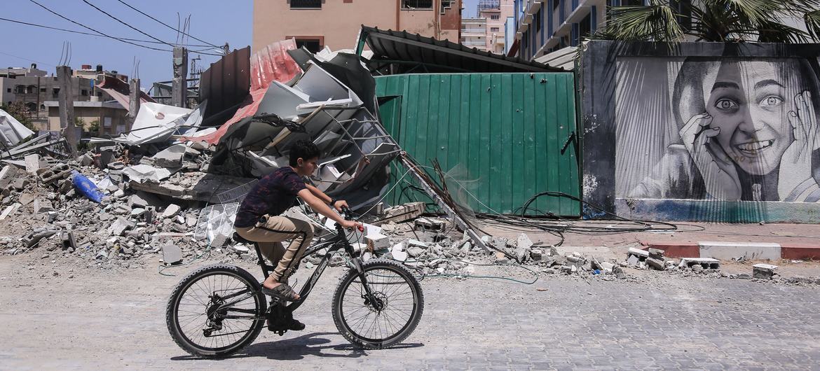 Un niño monta una bicicleta cerca de los edificios destruidos por los ataques israelíes en la Franja de Gaza, Palestina.