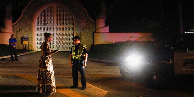Un oficial de policía habla con una mujer frente a la casa de Mar-a-Lago del expresidente de los Estados Unidos, Donald Trump, después de que Trump dijera que los agentes del FBI la allanaron, en Palm Beach, Florida, Estados Unidos, el 8 de agosto de 2022. 