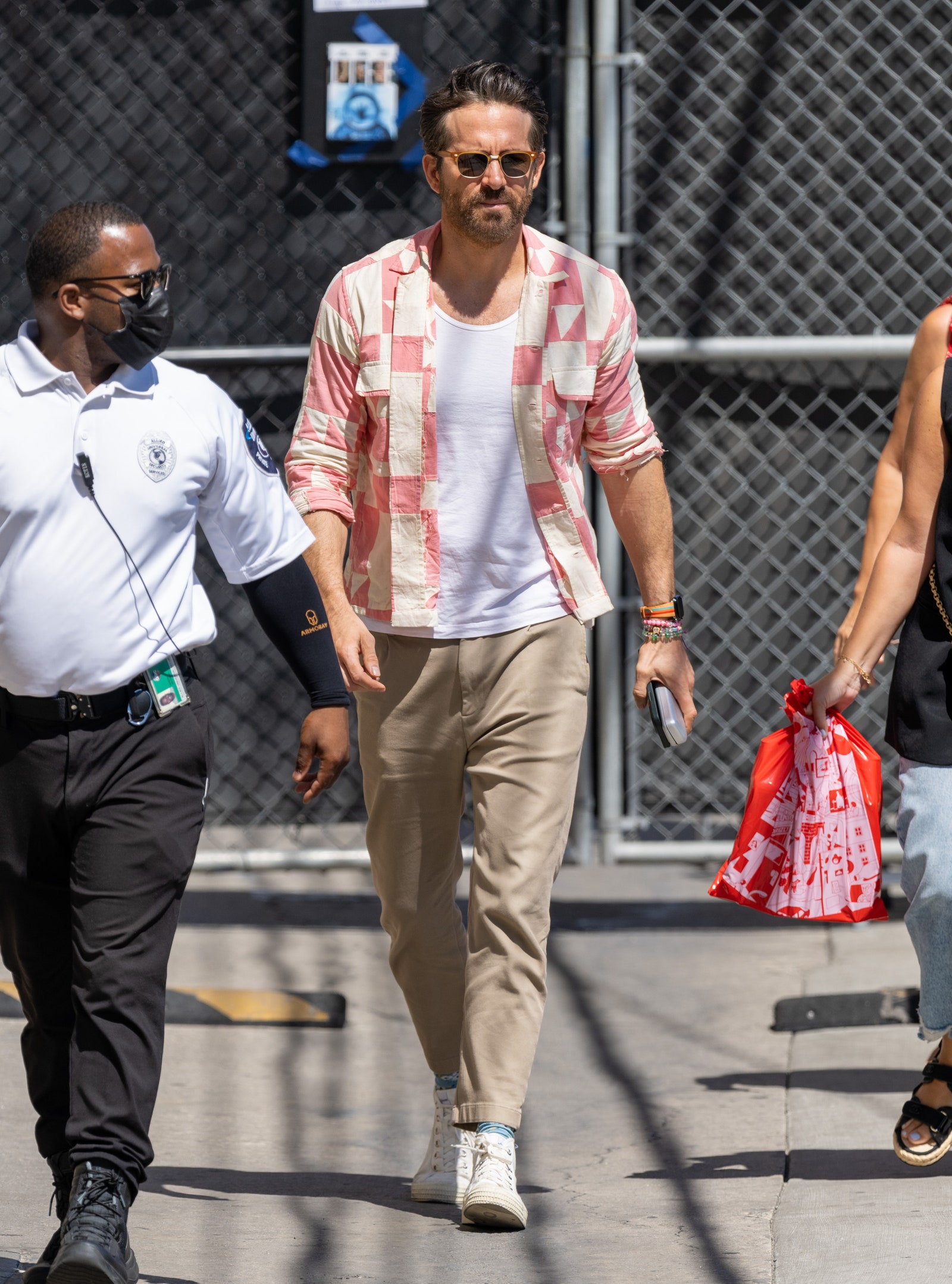 Ryan Reynolds usa pantalones de tenis marrones, camisa blanca de tenis rosa y camiseta sin mangas