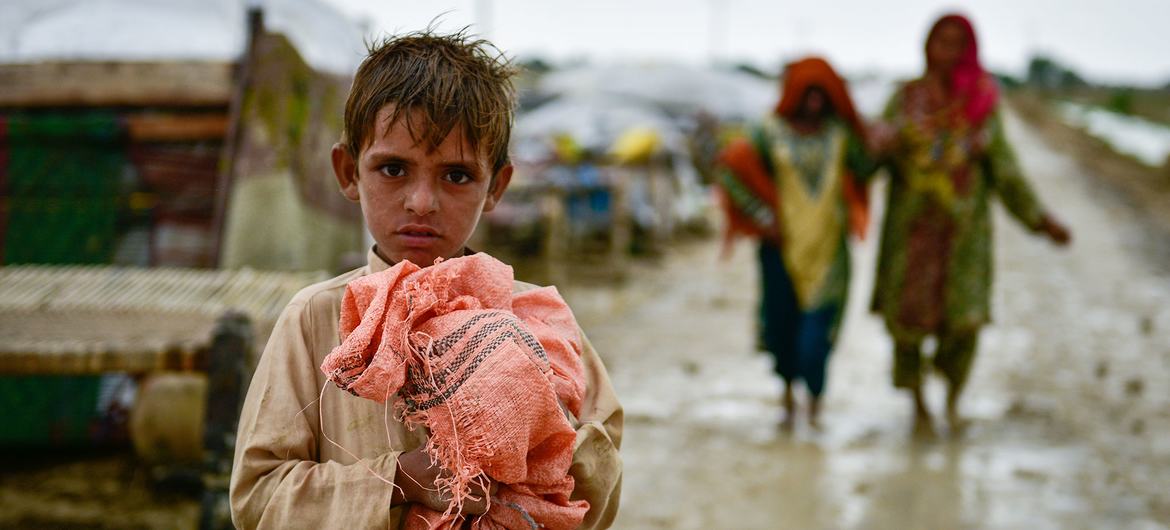 Un niño se aferra a sus pertenencias mientras las familias se trasladan a zonas más seguras tras las inundaciones en la provincia pakistaní de Baluchistán.