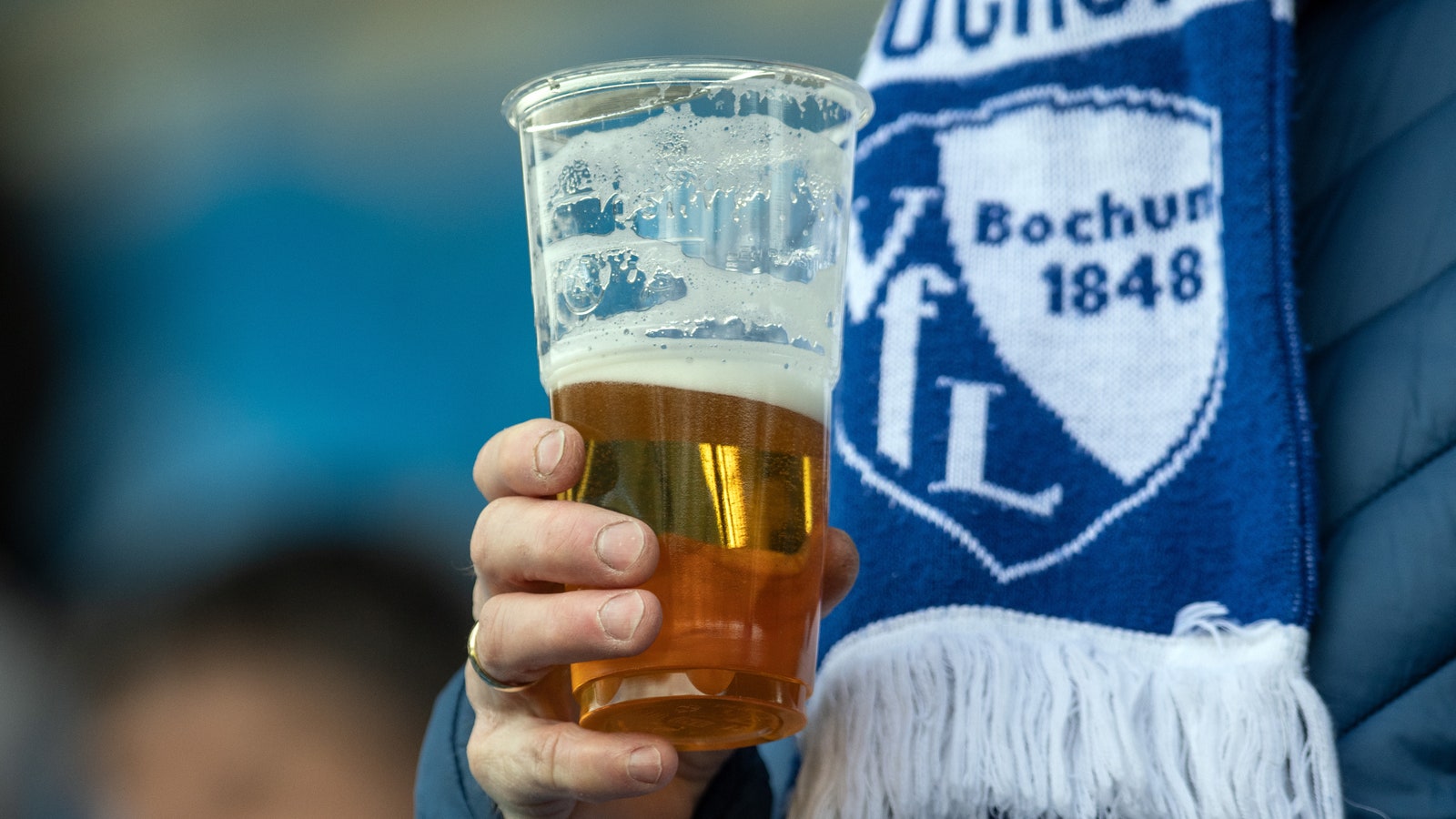 Vaso de cerveza sostenido por la asociación fanático del fútbol