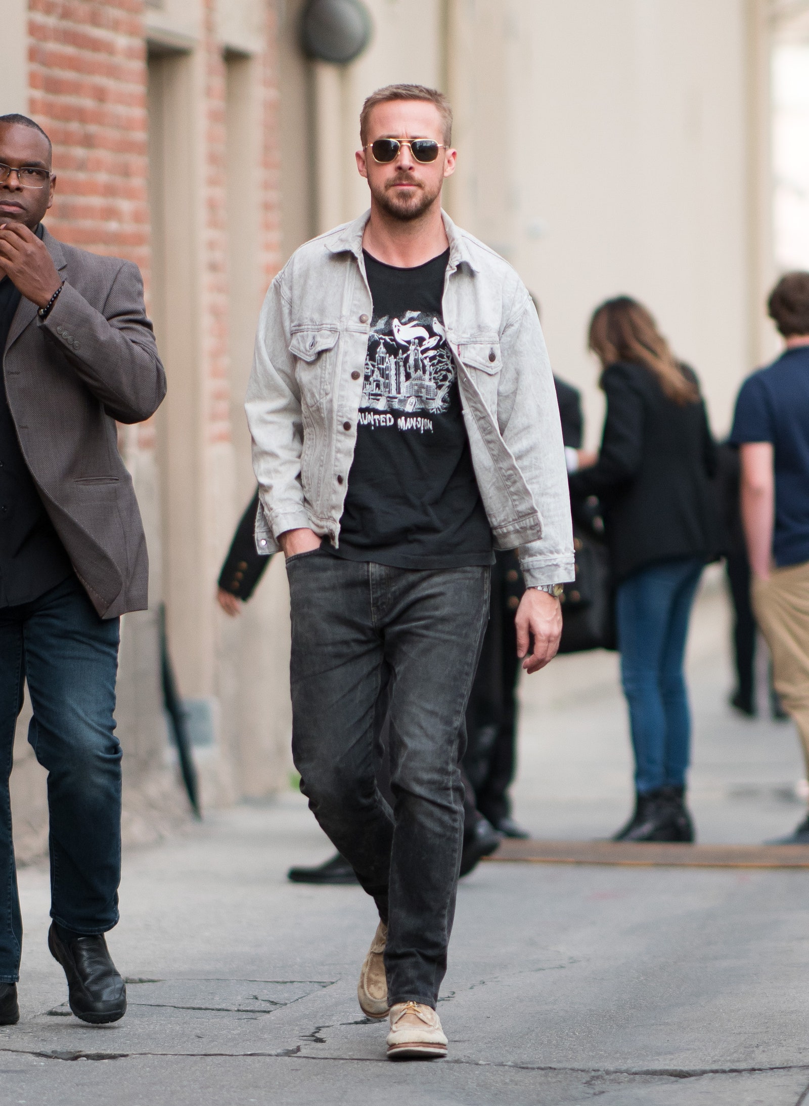 Ryan Gosling usa jeans, botas, chaqueta de mezclilla y lentes de sol.