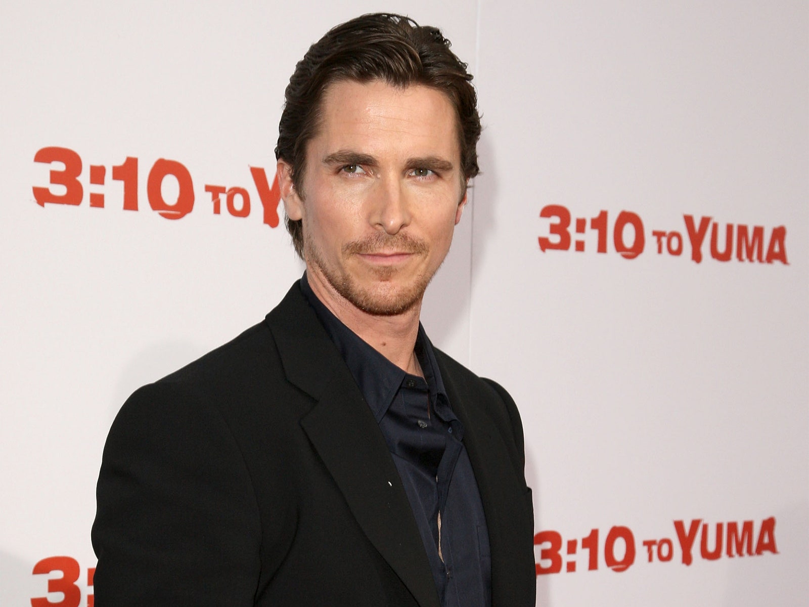 Christian Bale viste traje negro con camisa negra