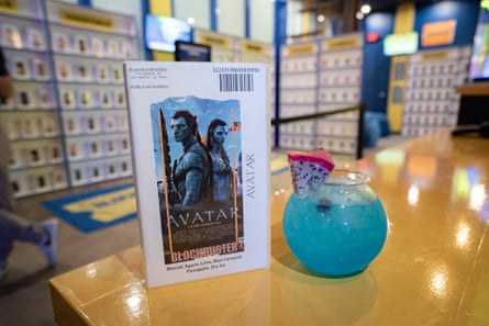 bebida azul en un vaso con forma de pecera junto al estuche del video Avatar