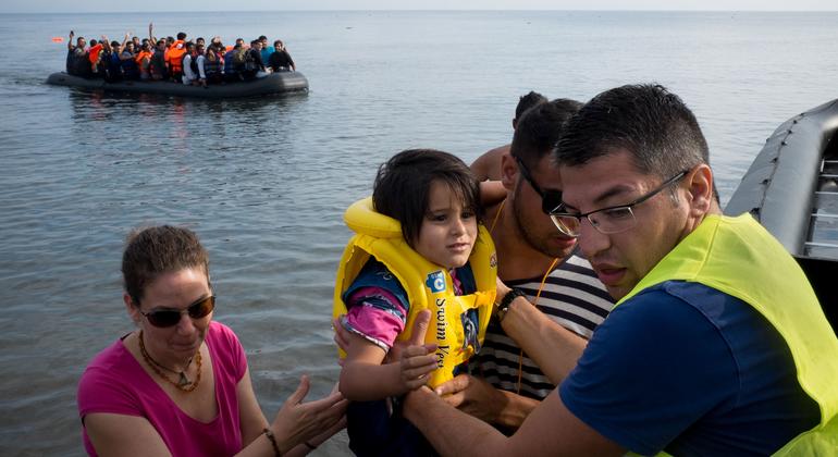Un voluntario ayuda a los refugiados recién llegados a desembarcar de un gran bote de goma en la isla griega de Lesbos.  (Foto de archivo)