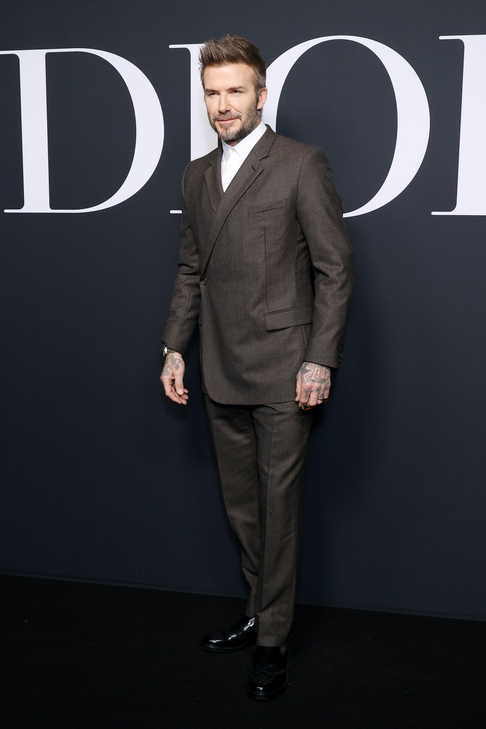 David Beckham viste traje gris con camisa blanca en el desfile de Dior