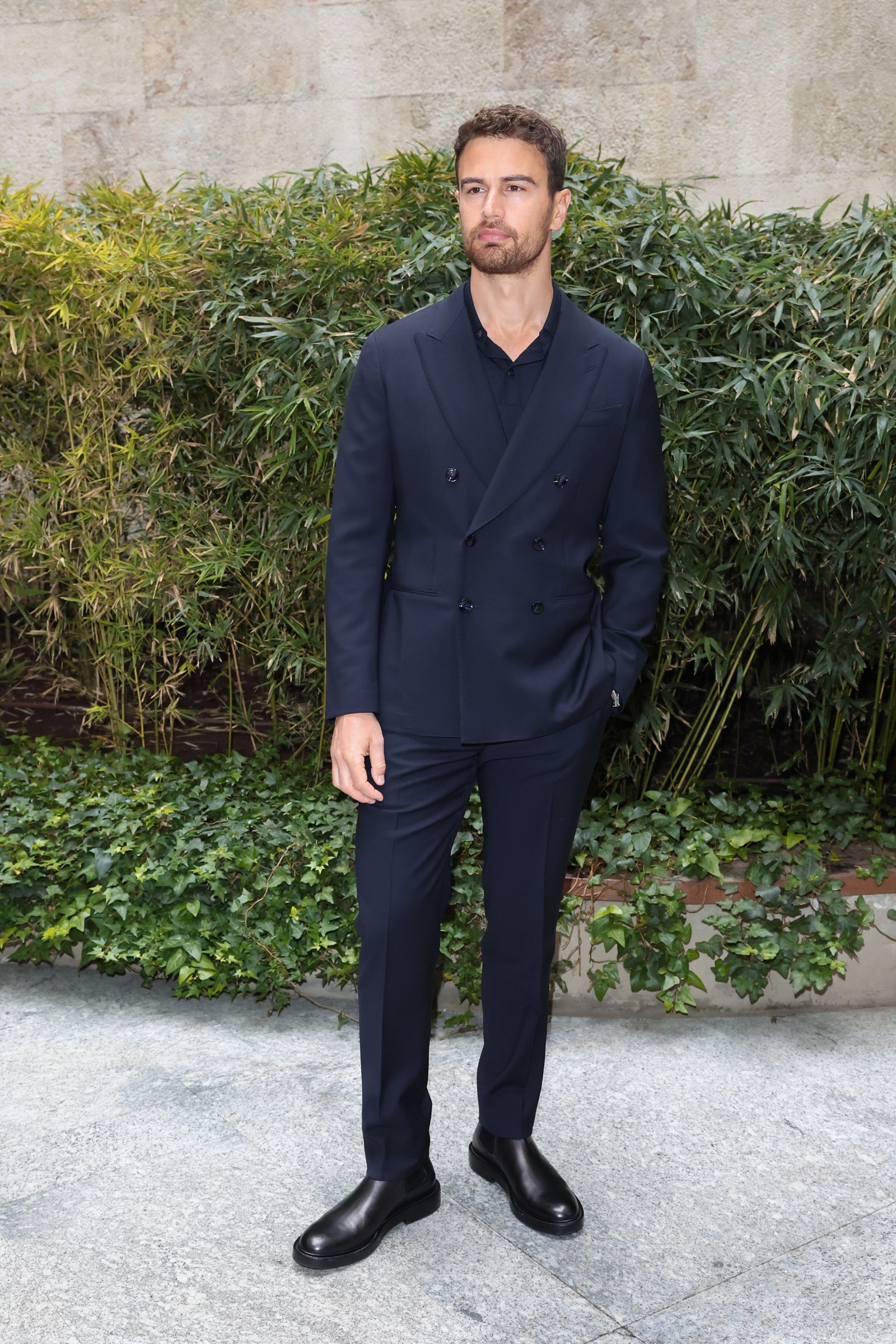 Theo James viste un traje azul marino de Giorgio Armani en la Semana de la Moda de Milán