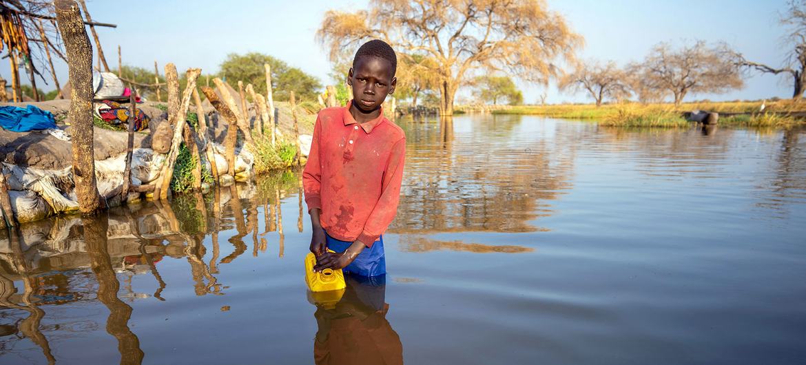 Un niño recoge agua en un pueblo afectado por graves inundaciones en Jonglei, Sudán del Sur.