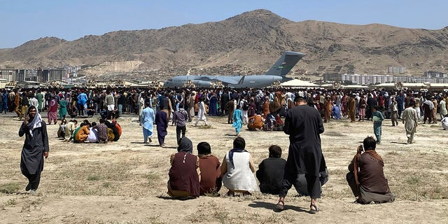 Cientos de personas se reúnen cerca de un avión de transporte C-17 de la Fuerza Aérea de EE. UU. en un perímetro del aeropuerto internacional de Kabul, Afganistán, el 17 de agosto de 2021.