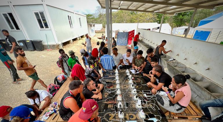 Migrantes y refugiados cargando sus teléfonos en un enchufe en la Estación de Recepción de Migrantes luego de cruzar la selva del Darién.