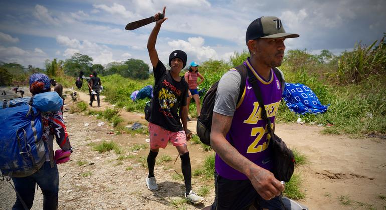 Migrantes agotados dan los últimos pasos para salir del Tapón del Darién y entrar en una comunidad.