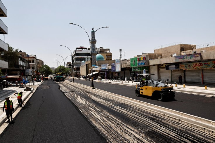 Trabajadores iraquíes colocan asfalto mientras se pavimenta una calle de Al-Karada en Bagdad