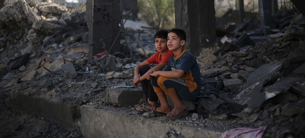 Dos niños se sientan entre los escombros de lo que queda de su casa en la ciudad de Rafah, en el sur de la Franja de Gaza.