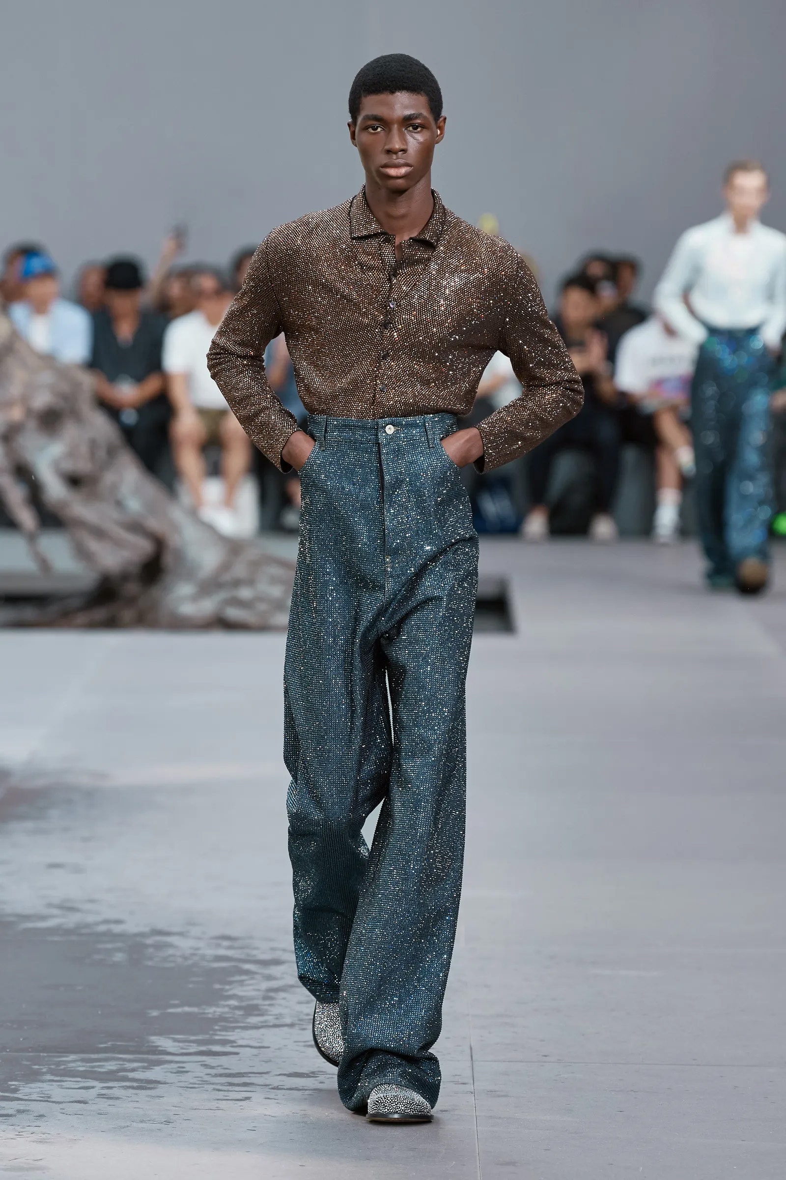 Modelo viste camisa y pantalones brillantes en el desfile Loewe SS 24